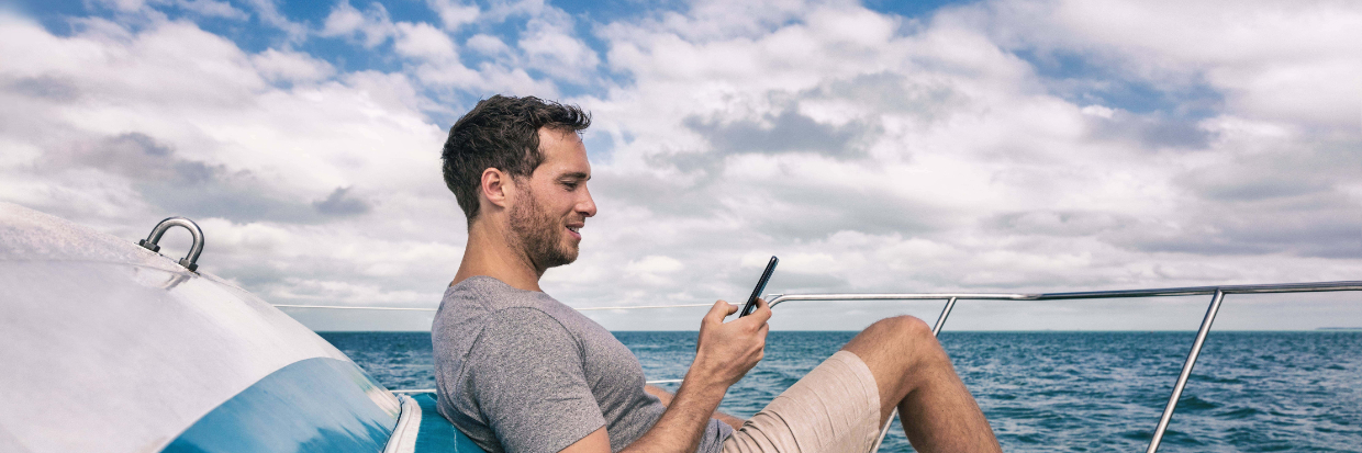man on boat sitting back looking at phone